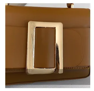 Detail of premium caramel leather handbag featuring a large golden metal buckle
