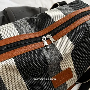 Detalle de cremalleras metálicas y textura de lona a rayas en bolso de viaje