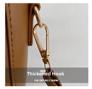 Close-up of durable golden metal hook and stitching on brown leather handbag strap