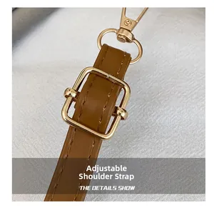 Detail of brown leather adjustable shoulder strap with gold buckle and lobster clasp