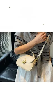 Detail of elegant cream shoulder bag with gold oval clasp and adjustable strap