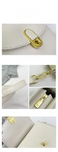 Close-up of white leather handbag featuring gold clasp hardware and engraved zipper detail
