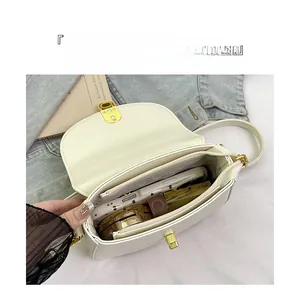 Interior view of off-white leather saddle bag showing main compartment and zip pocket