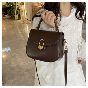 Detailed close-up of dark brown vintage leather crossbody bag with gold oval clasp