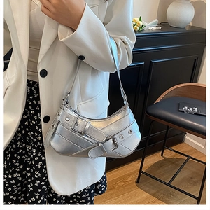 Silver metallic underarm bag with punk buckles and eyelets on a model's shoulder