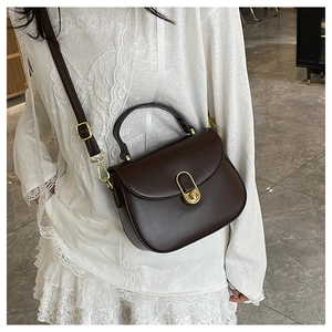 Detail view of a vintage dark brown crescent bag with a gold clasp on a model