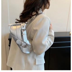 Detail of silver metallic saddle bag with punk buckles on white suit blazer