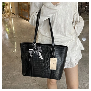 Detail of black crocodile texture tote bag with a decorative polka dot ribbon bow