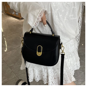 Detail of vintage black saddle bag with golden oval clasp and polished top handle