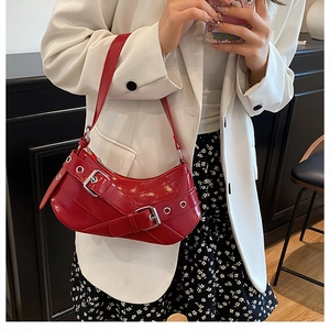 Détail d'un sac demi-lune rouge brillant avec boucle de ceinture et œillets