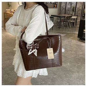 Detail view of large brown crocodile embossed tote bag with decorative silk scarf