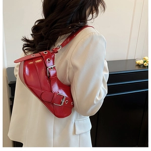 Gros plan d'un sac à bandoulière en cuir verni rouge avec boucles punk tendance