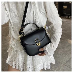 Detail of elegant black saddle bag with golden metal buckle on a white lace dress