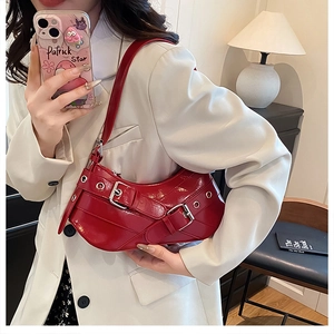 Détail du sac baguette en cuir verni rouge avec boucles métalliques et œillets de style
