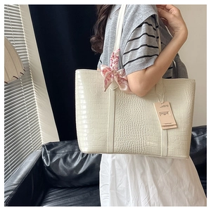 Detail of cream crocodile embossed tote bag featuring a pink floral silk scarf on strap
