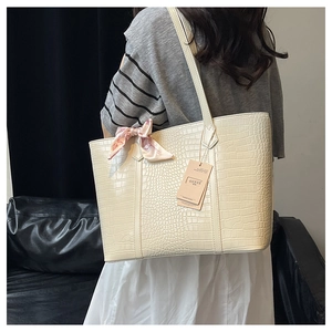 Detail of crocodile embossed tote bag in beige with decorative pink floral scarf handle