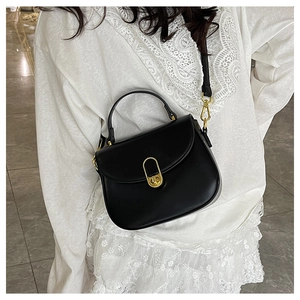 Detail of elegant black crossbody bag featuring a distinctive oval gold metal lock clasp