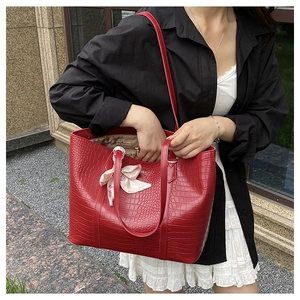 Detail of red croc-embossed tote bag featuring floral scarf and long shoulder straps