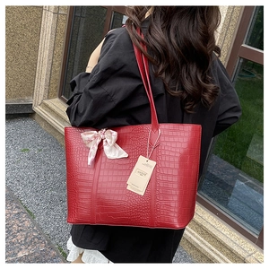 Detailed view of red crocodile pattern tote bag with decorative floral silk scarf on handle