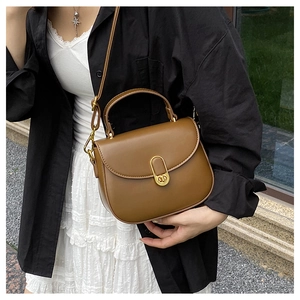 Detail of elegant brown leather handbag with gold oval twist lock and adjustable shoulder strap