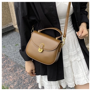 Detail shot of vintage saddle bag with golden clasp and brown vegan leather texture