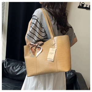 Detail of light brown tote bag featuring crocodile texture and floral silk scarf accessory