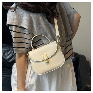 Detail showing creamy white textured saddle bag with gold oval twist lock and handle