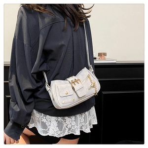 Detail of crossbody bag featuring star charm, rivet accents and metal hardware details