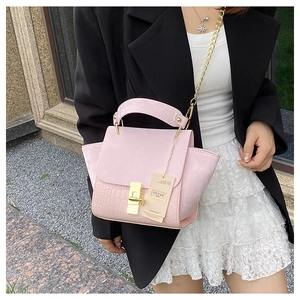 Pink crocodile pattern handbag detail with gold lock and chain strap on a black blazer