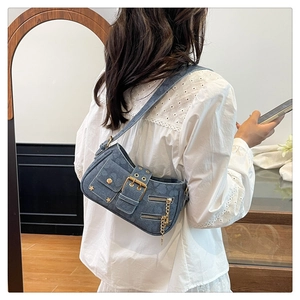 Detail of star rivets and metal buckle on blue denim Y2K style underarm shoulder bag