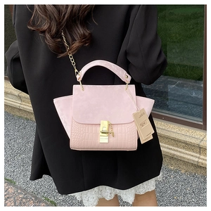 Detail of pink crocodile embossed leather bag with gold buckle and chain shoulder strap