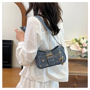 Detailed shot of blue denim shoulder bag with golden star charms and rivets on the strap