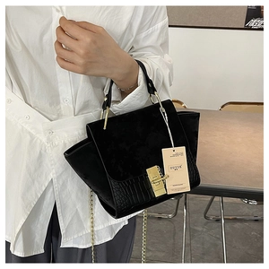Detail of vintage matte black and crocodile pattern leather handbag with gold twist lock