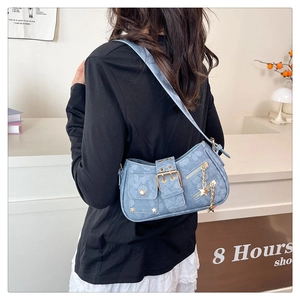 Detail of light blue denim Y2K shoulder bag featuring metal buckles and star charms