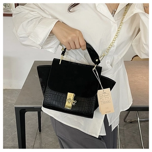 Detail of black winged handbag featuring faux crocodile texture and gold chain strap