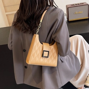 Brown quilted bucket bag with chain strap shown on a model in a modern office setting