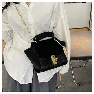 Detail of black crocodile texture handbag with matte flap and gold chain strap