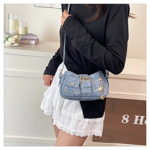 Detail of blue denim shoulder bag featuring star charms and golden metal buckles