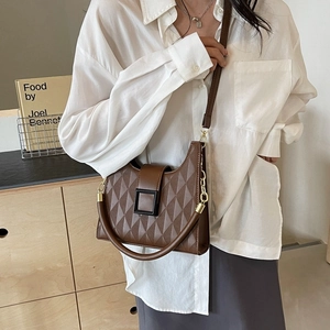 Quilted dark brown bucket bag with dual shoulder straps shown in a minimalist home setting