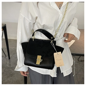 Detail of black crocodile texture and matte leather patchwork with gold chain strap