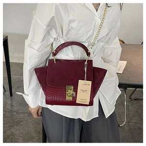 Close-up of burgundy crocodile pattern textured leather and gold chain detail on handbag