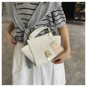 Close-up of white croc-embossed handbag with golden chain strap and lock buckle details