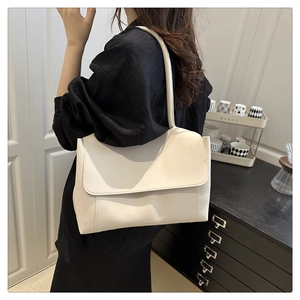 Detail of minimalist cream leather tote bag shown worn by a model in a modern home setting