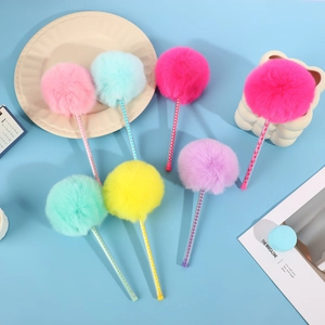Penne con pom pon di peluche in colori pastello su una scrivania blu creativa