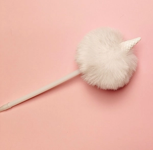 Dettaglio del pompon bianco soffice e della penna a forma di gufo su sfondo rosa