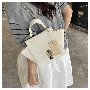 Detail of white crocodile-embossed leather handbag with gold turn-lock and chain strap