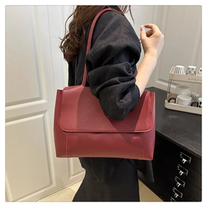 Detail of dark red matte leather tote bag featuring magnetic flap and slim strap