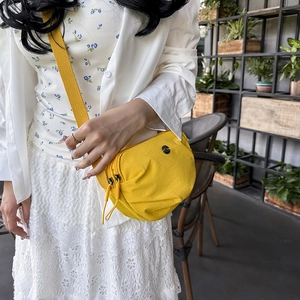 Vibrant yellow nylon crossbody bag for daily use shown on a model in a cafe setting