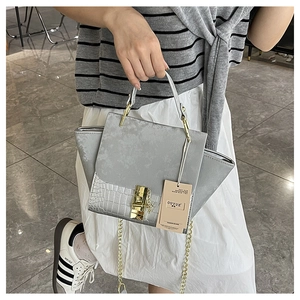 Detail of grey suede and silver crocodile pattern wings bag with golden metal hardware