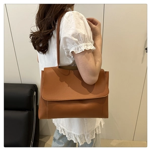 Detailed view of caramel PU leather tote bag showing crossbody style on a model